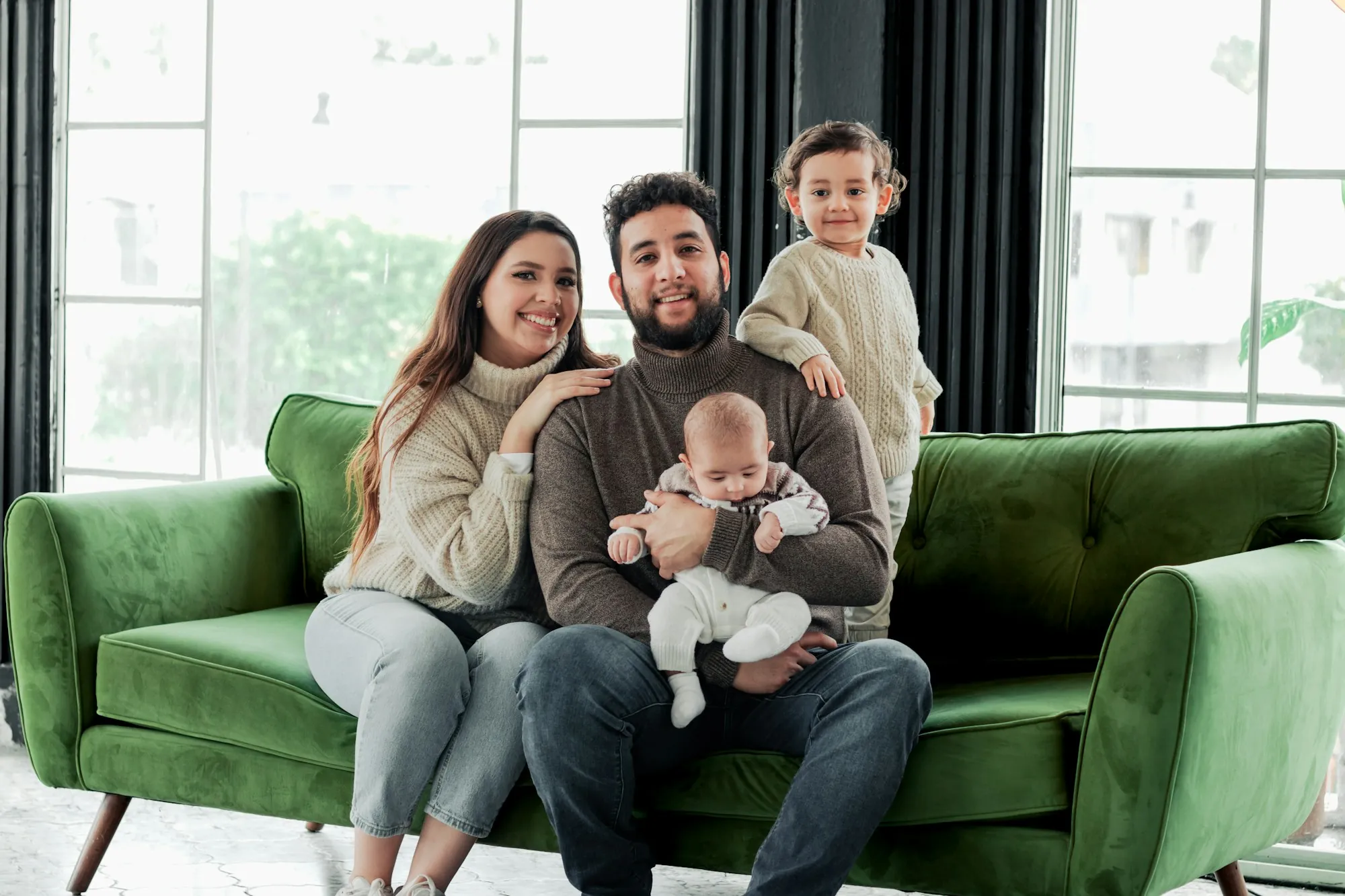 Family with young children sitting on a green sofa